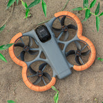 DJI Avata 360 landed in dirt. The high-visibility orange STARTRC drone guards ensure effortless drone retrieval in grass or forests.
