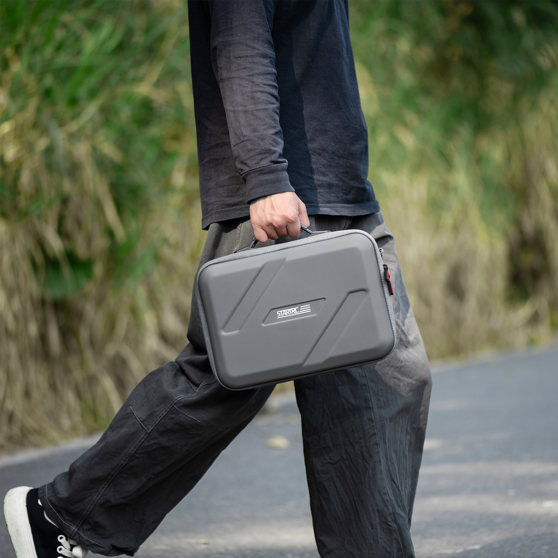 A creator walking outdoors with the STARTRC DJI Lito carry bag. The included adjustable shoulder strap makes it easy to grab and go on location.