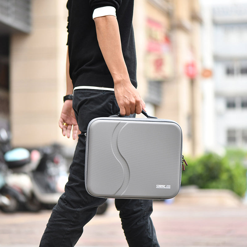 A traveler carrying the STARTRC DJI Neo 2 PU bag by its retractable top handle for convenient on-the-go use.