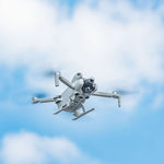 Aerial view of a compact camera drone flying smoothly in the sky with the all-terrain landing legs attached, preserving full flight performance.