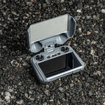 DJI RC2 controller resting on rocky ground with the 180-degree rotatable sun hood open, preventing screen glare in bright sunlight.