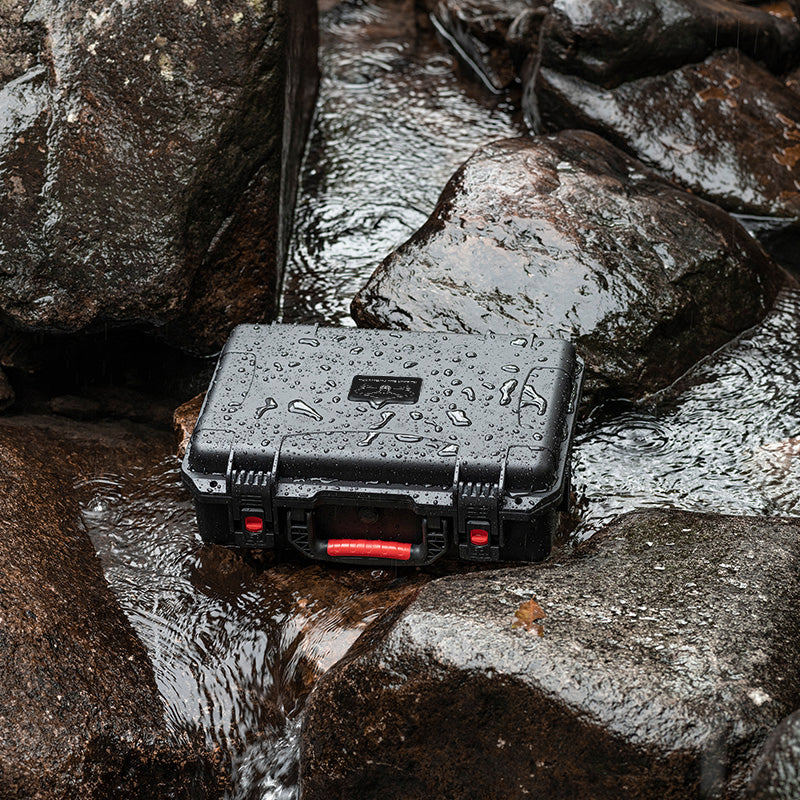 The rugged STARTRC carrying case sitting securely on wet outdoor rocks, demonstrating its IP67 waterproof and weather-resistant capabilities for adventure filmmakers.