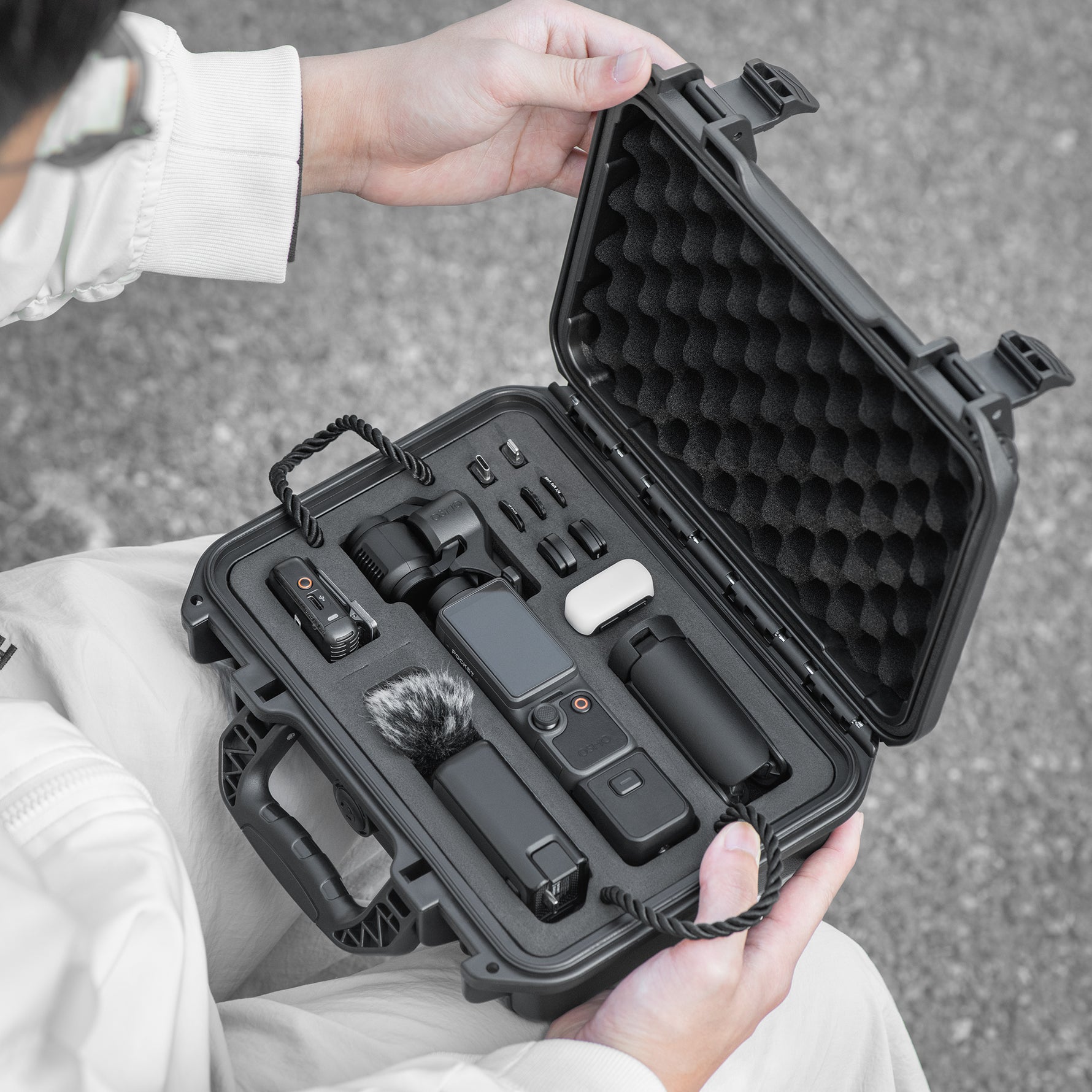 A creator accessing their DJI Osmo Pocket 4 gear outdoors from the STARTRC travel case. Shock-absorbing EVA interior keeps equipment safe and scratch-free on any adventure.