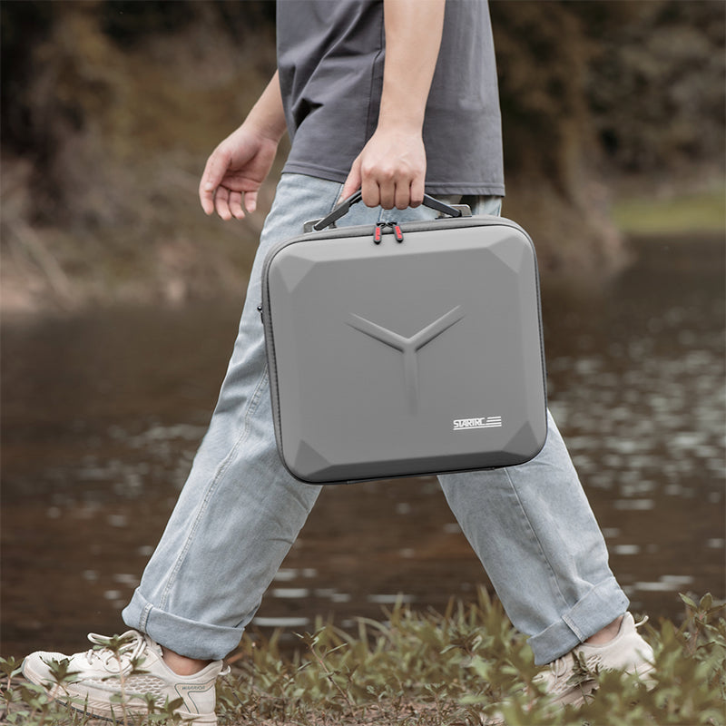 Weekend adventurer easily carrying the lightweight DJI Mavic 4 Pro hard case by the ergonomic handle while walking outdoors.