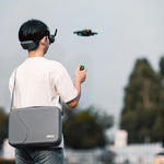 A travel vlogger wearing the portable DJI Avata 2 crossbody bag while hiking, illustrating its lightweight and hands-free design.