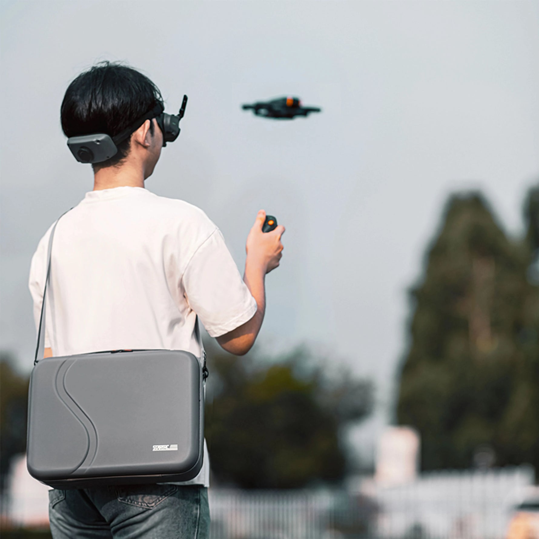 A travel vlogger wearing the portable DJI Avata 2 crossbody bag while hiking, illustrating its lightweight and hands-free design.