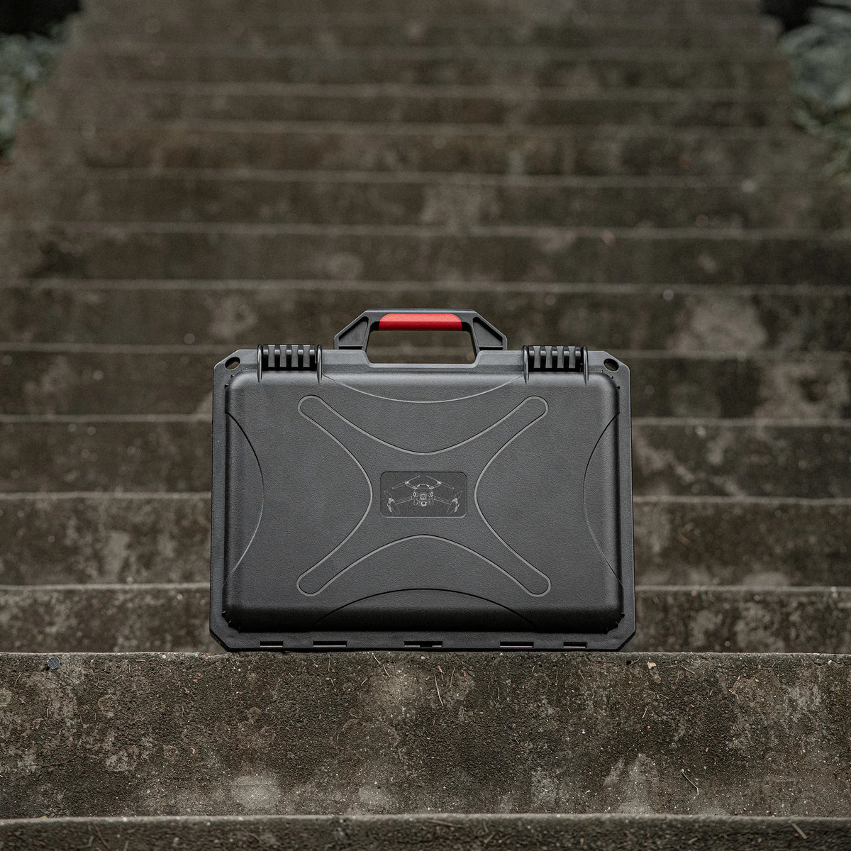 Closed drone equipment box sitting on outdoor stone steps, a reliable travel companion for photographers and outdoor enthusiasts.