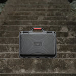 Closed drone equipment box sitting on outdoor stone steps, a reliable travel companion for photographers and outdoor enthusiasts.