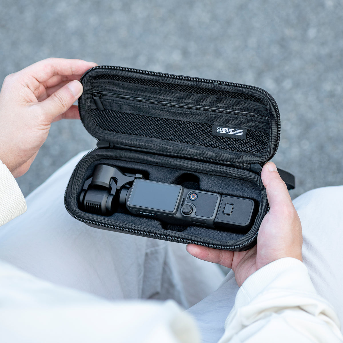 A user holding the portable STARTRC Pocket 4 case, demonstrating its compact size and easy carry for outdoor adventures or travel.
