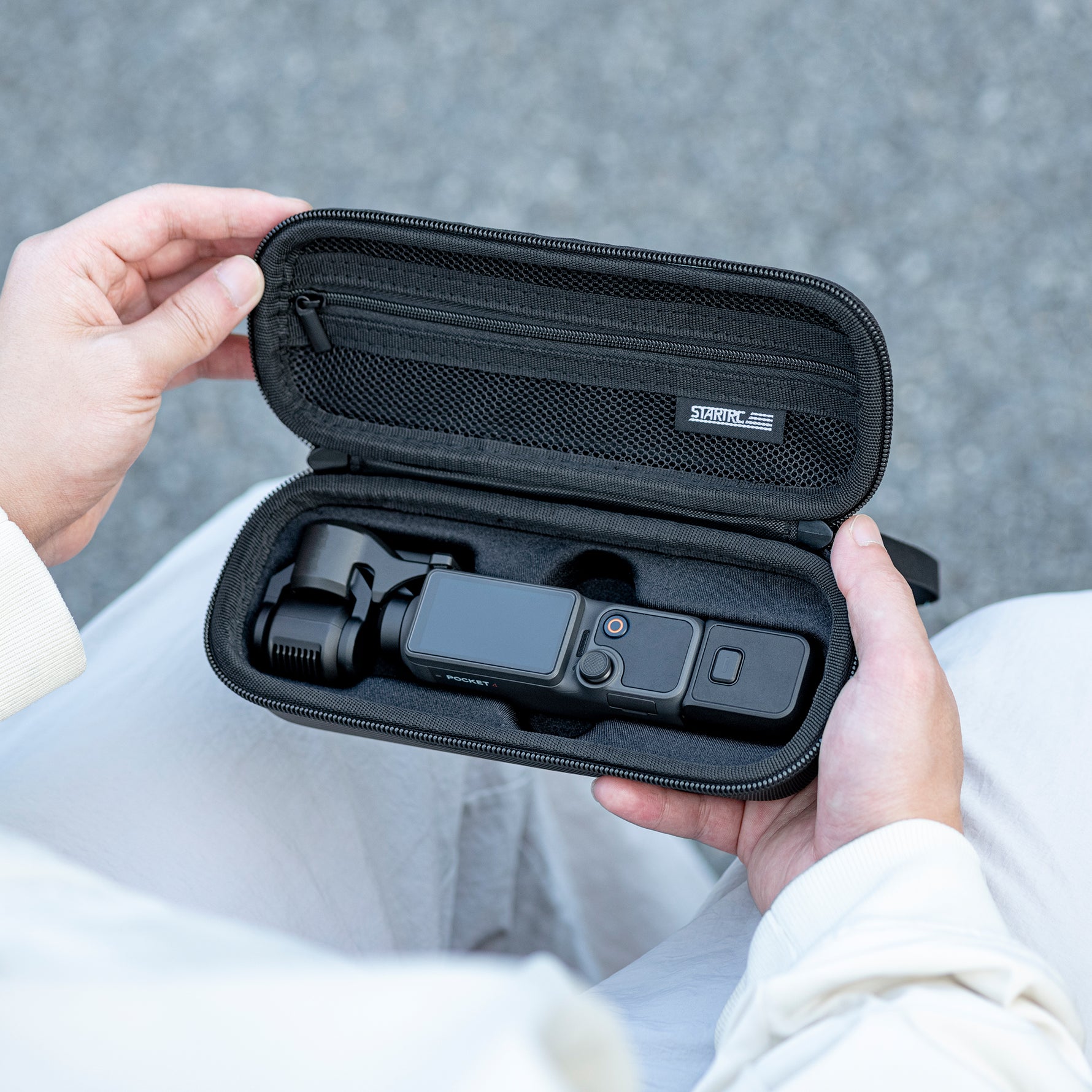 A user holding the portable STARTRC Pocket 4 case, demonstrating its compact size and easy carry for outdoor adventures or travel.