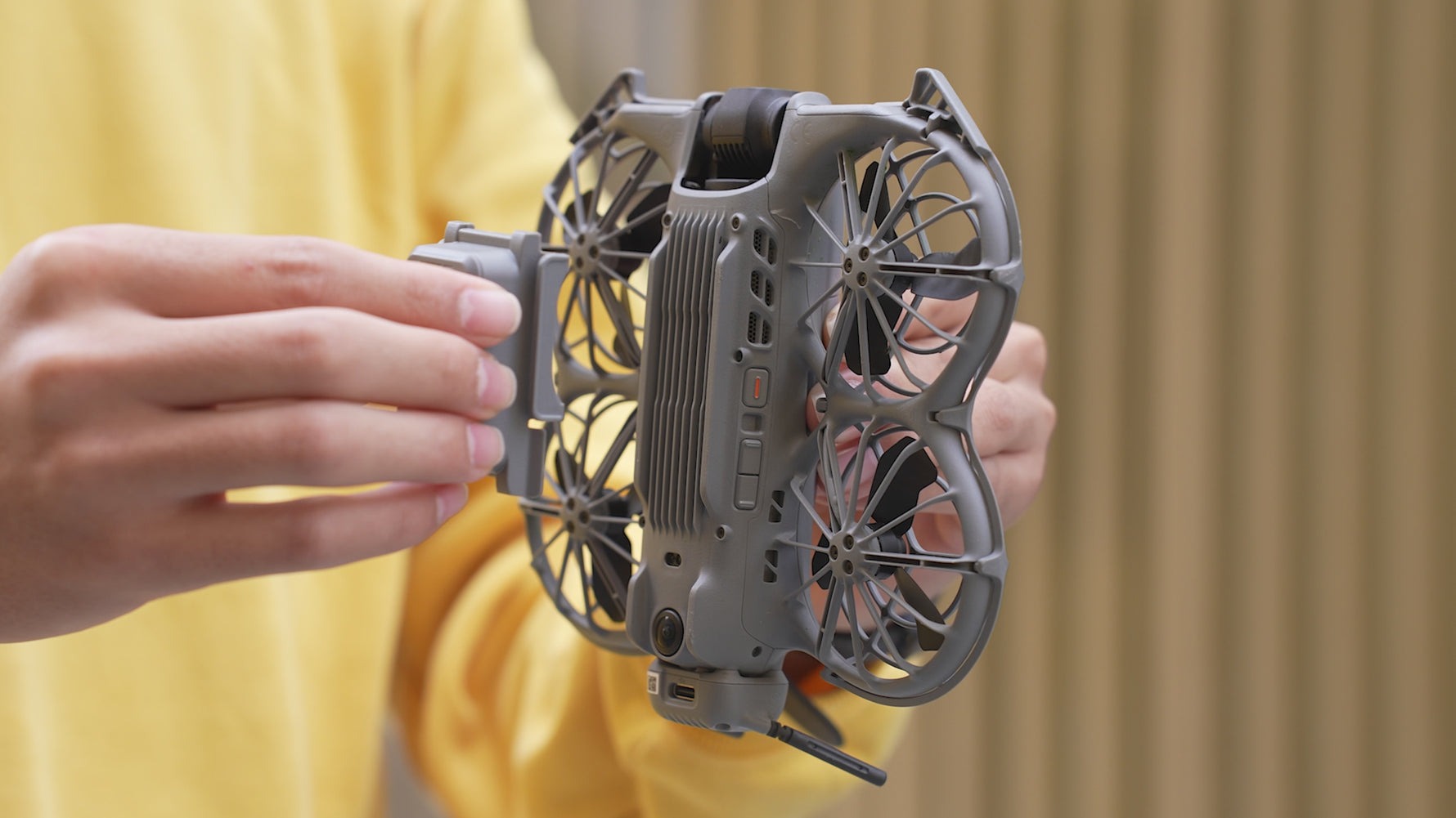 A user demonstrating the quick and easy snap-on installation of the STARTRC LED landing gear onto the DJI Neo 2 drone.