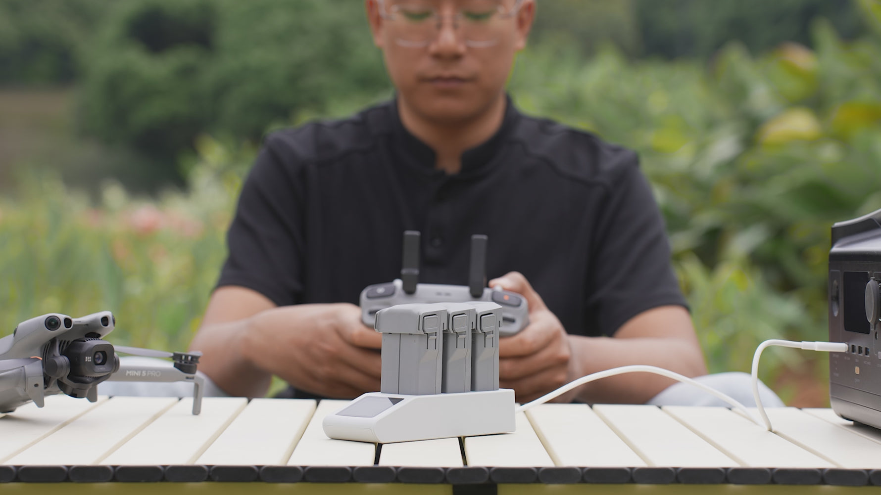 Lifestyle shot of a drone pilot using the intelligent screen charging manager to sequentially charge multiple Mini 5 Pro batteries on a desk.