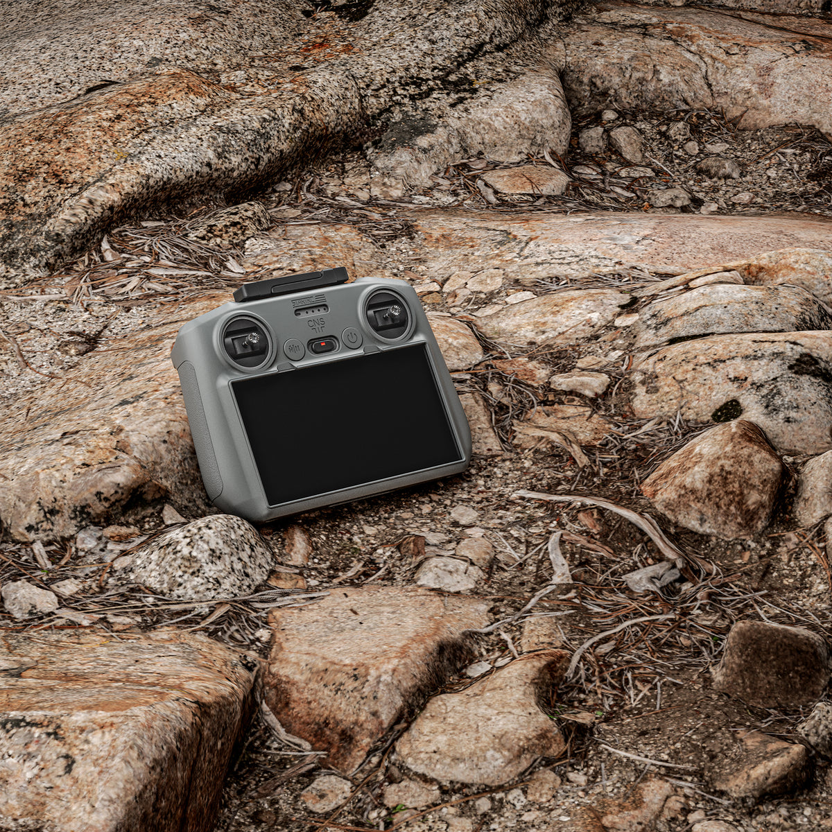 A DJI RC 2 remote protected by the STARTRC silicone cover resting on rugged rocks, highlighting its dust-proof, oil-resistant, and washable features.