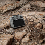 A DJI RC 2 remote protected by the STARTRC silicone cover resting on rugged rocks, highlighting its dust-proof, oil-resistant, and washable features.