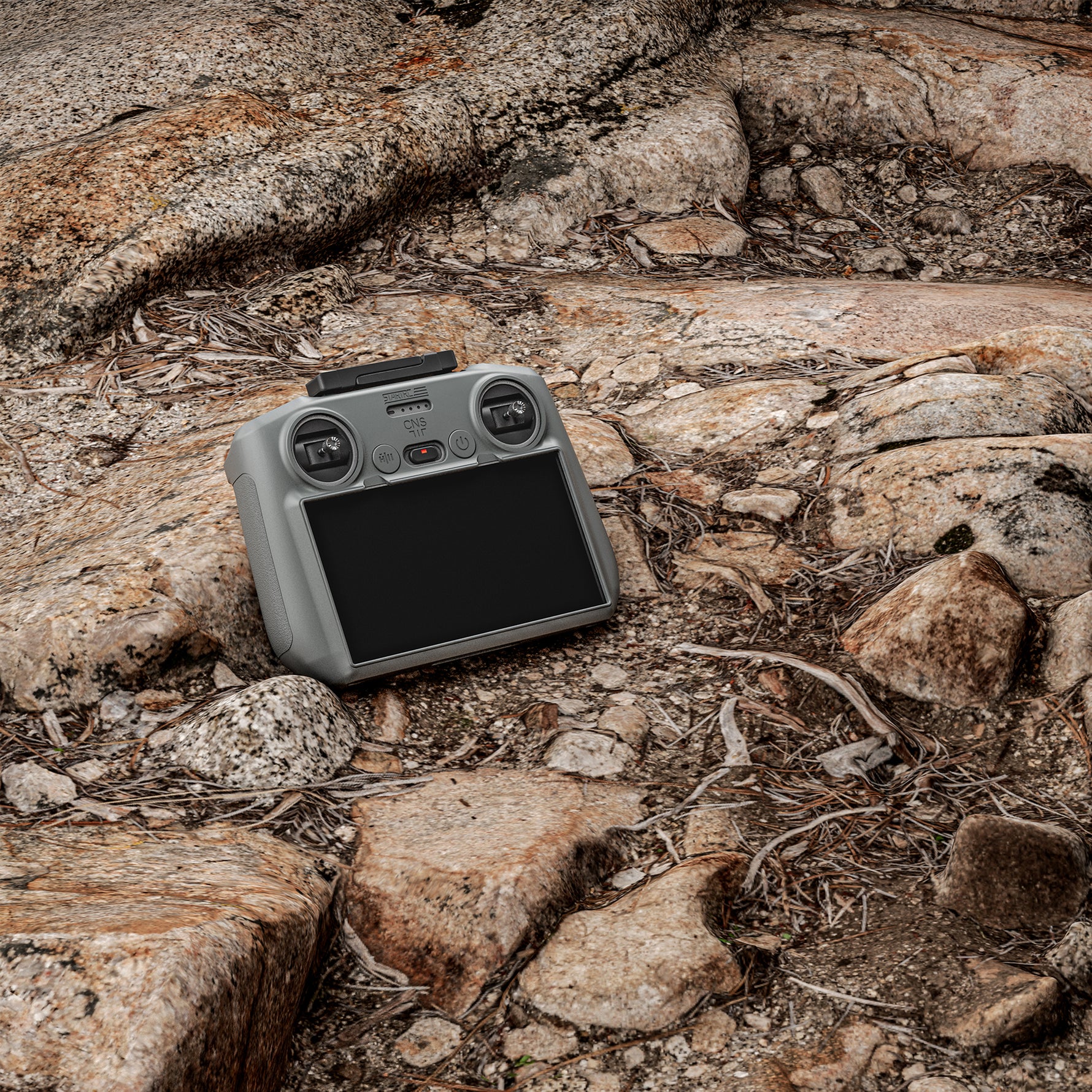 A DJI RC 2 remote protected by the STARTRC silicone cover resting on rugged rocks, highlighting its dust-proof, oil-resistant, and washable features.