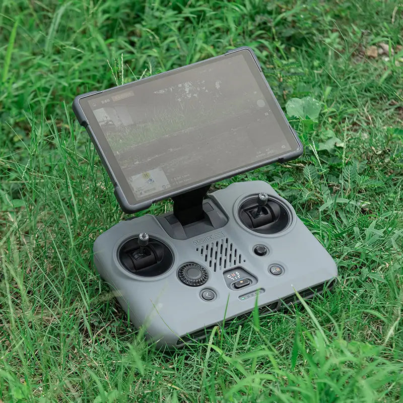 The DJI RC PRO 2 remote controller resting safely on outdoor grass, shielded from dirt, dust, and scratches by the shockproof silicone case.
