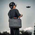 A drone pilot carrying the STARTRC DJI Avata 2 travel hard case during an outdoor hike, demonstrating its portability for adventure enthusiasts.